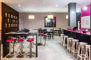 Un área de bar moderna con varios taburetes, una barra y un espejo.