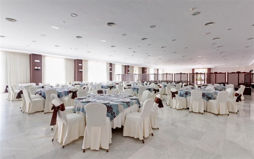 A large banquet hall with multiple round tables, each set with white chairs and tablecloths.