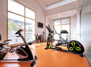 Un gimnasio con máquinas de cardio, dispensador de agua y ventanas amplias.