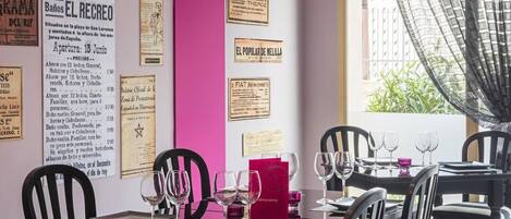 A restaurant interior with a pink accent wall, multiple menu boards, and a dining area with tables set for guests.