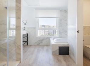 A modern bathroom with a bathtub, a shower, and a window with a view of buildings. - Melilla Puerto Hotel (Melilla)