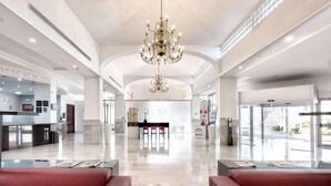Eine geräumige Lobby mit einer Kronleuchter, einer Rezeption und einer Sitzecke.