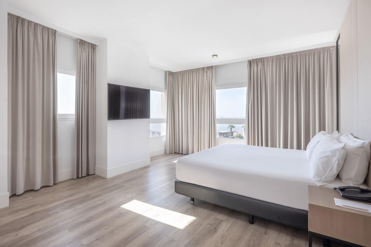 Una camera d'albergo con un letto grande, una TV a schermo piatto e vista sulla città.
