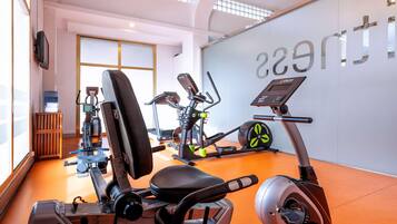 Un gimnasio con equipo de ejercicio, un dispensador de agua y una pared donde se lee la palabra 'gym'.