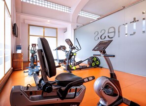 A gym with exercise equipment, a water cooler, and a wall with the word 'gym' visible.