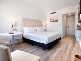 Una habitación de hotel con una cama, mesitas de noche, un escritorio y una silla.
