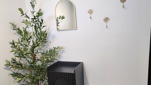 Una habitación con una planta en maceta, un banco, un espejo y apliques decorativos en la pared.