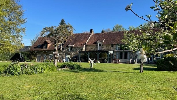 Ein großes, historisches Haus mit weitläufiger Rasenfläche und einer Windmühle im Vordergrund.