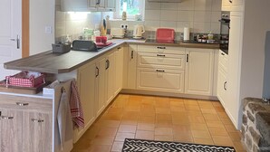 Eine Küche mit weißen Schränken, einer Holz Arbeitsplatte und einem gemusterten Teppich.