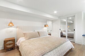 Une chambre à coucher avec un grand lit, des lampes de chevet, une table de chevet et un placard à portes coulissantes.