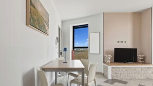 Una sala de estar moderna con comedor, un ventanal grande, un televisor de pantalla plana y una pared de acento de piedra.