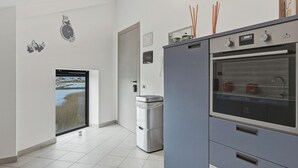 Una cocina moderna con horno integrado, refrigerador y ventana con vista al agua.