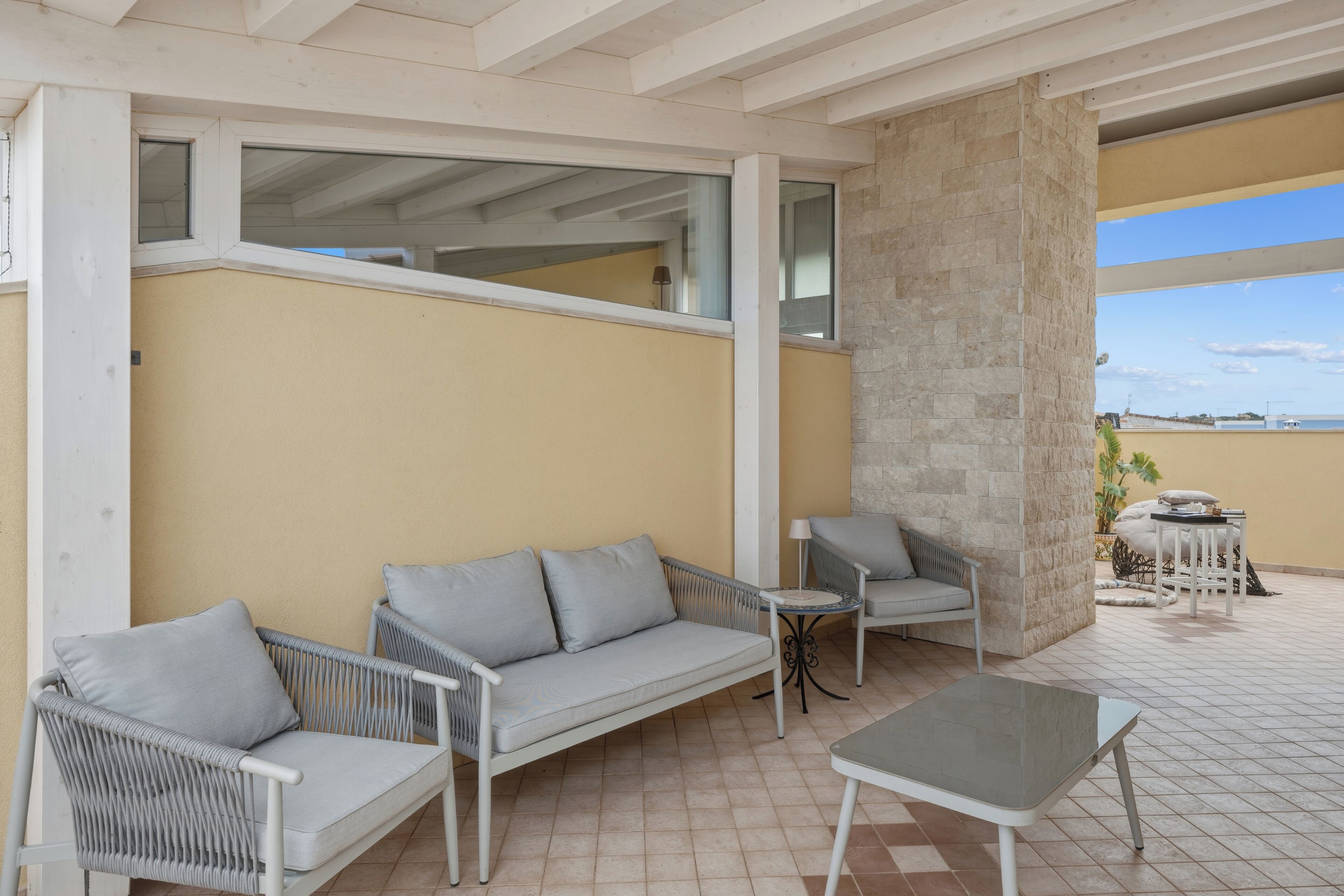 Un espace extérieur aménagé, abrité et doté d’un canapé, de chaises et d’une table.