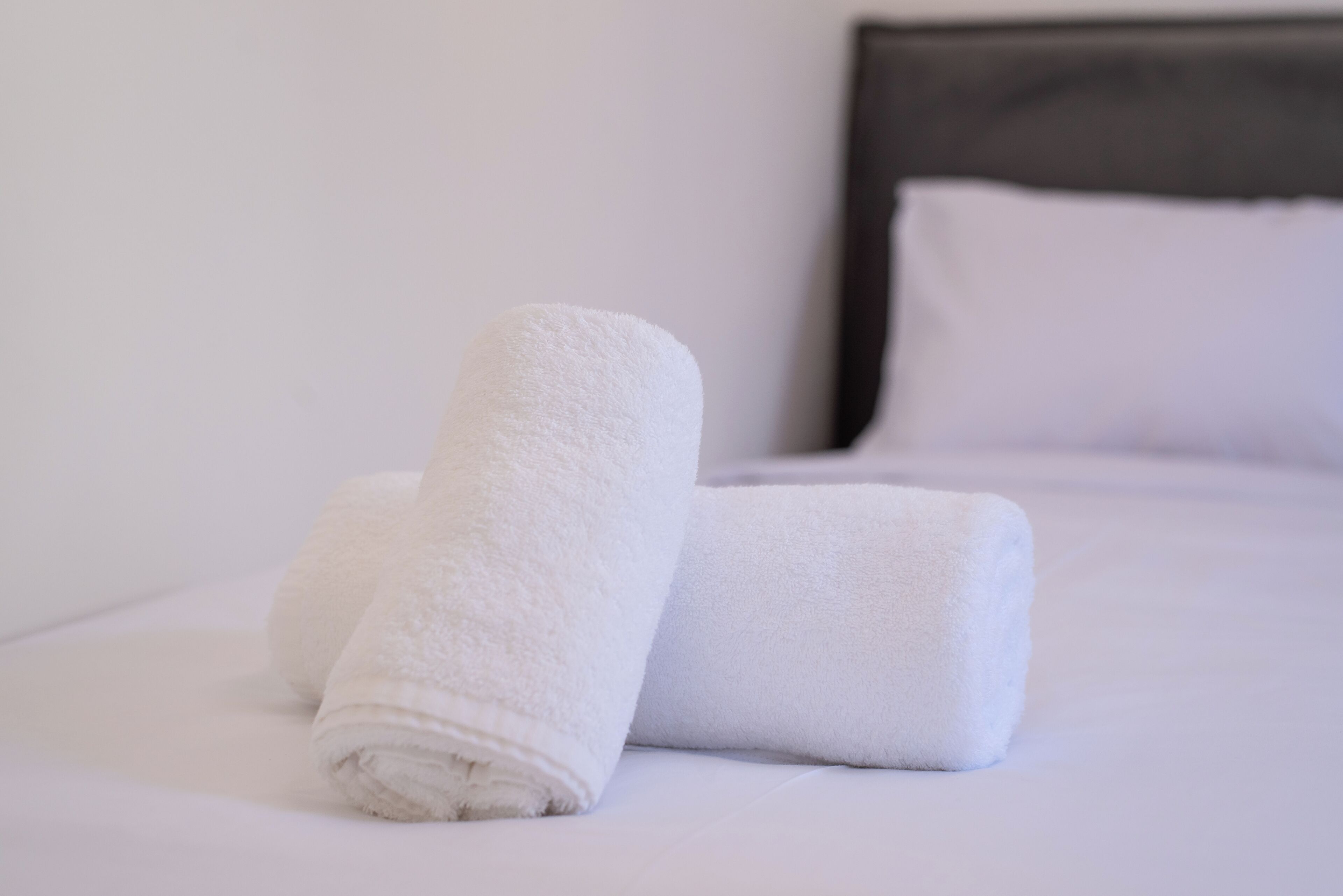A neatly made bed with white linens and pillows.