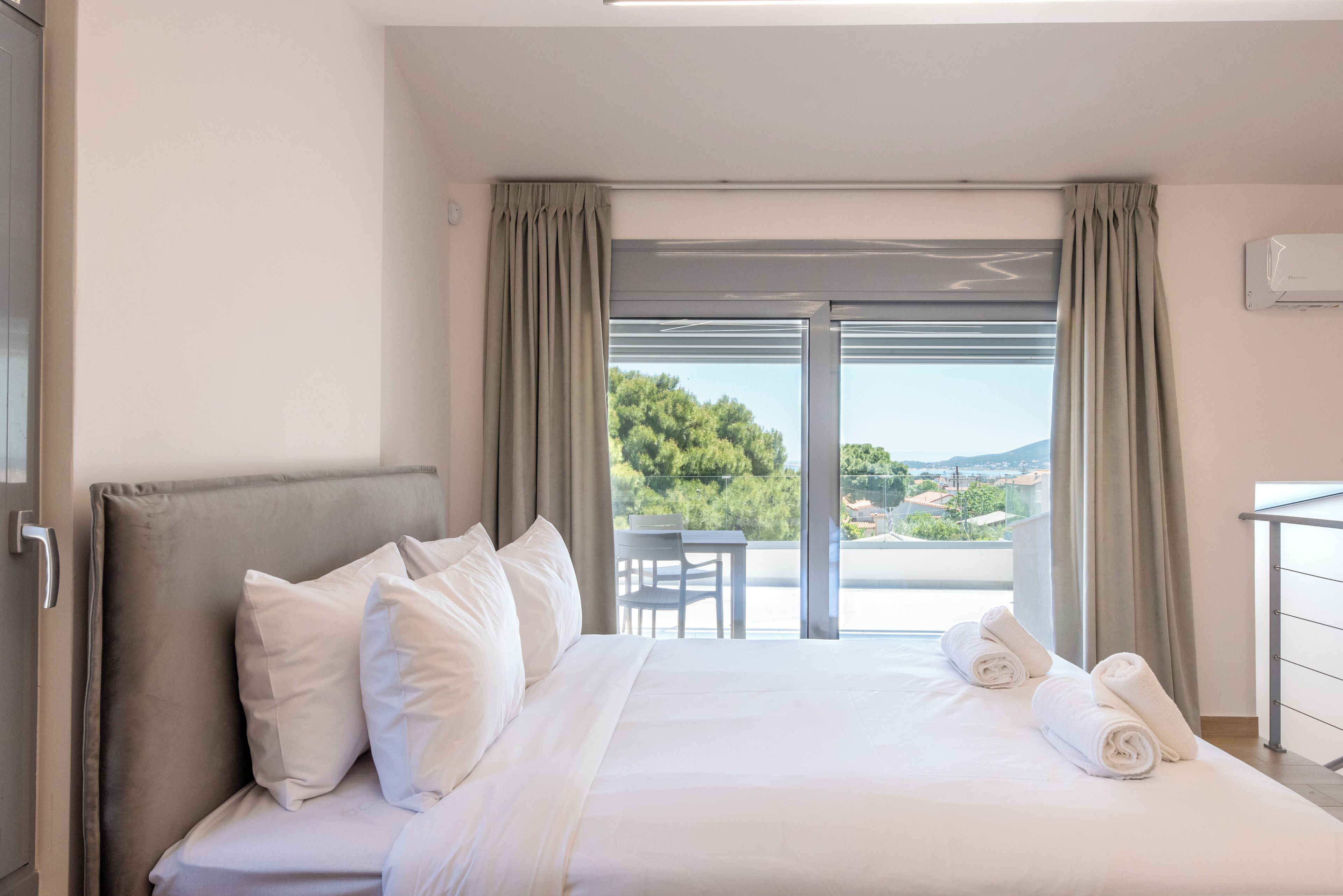 A hotel room with a bed, a view of the outdoors, a table, and a chair.