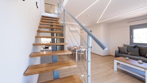 Un interior moderno con una escalera de madera, una zona de comedor y un sofá.