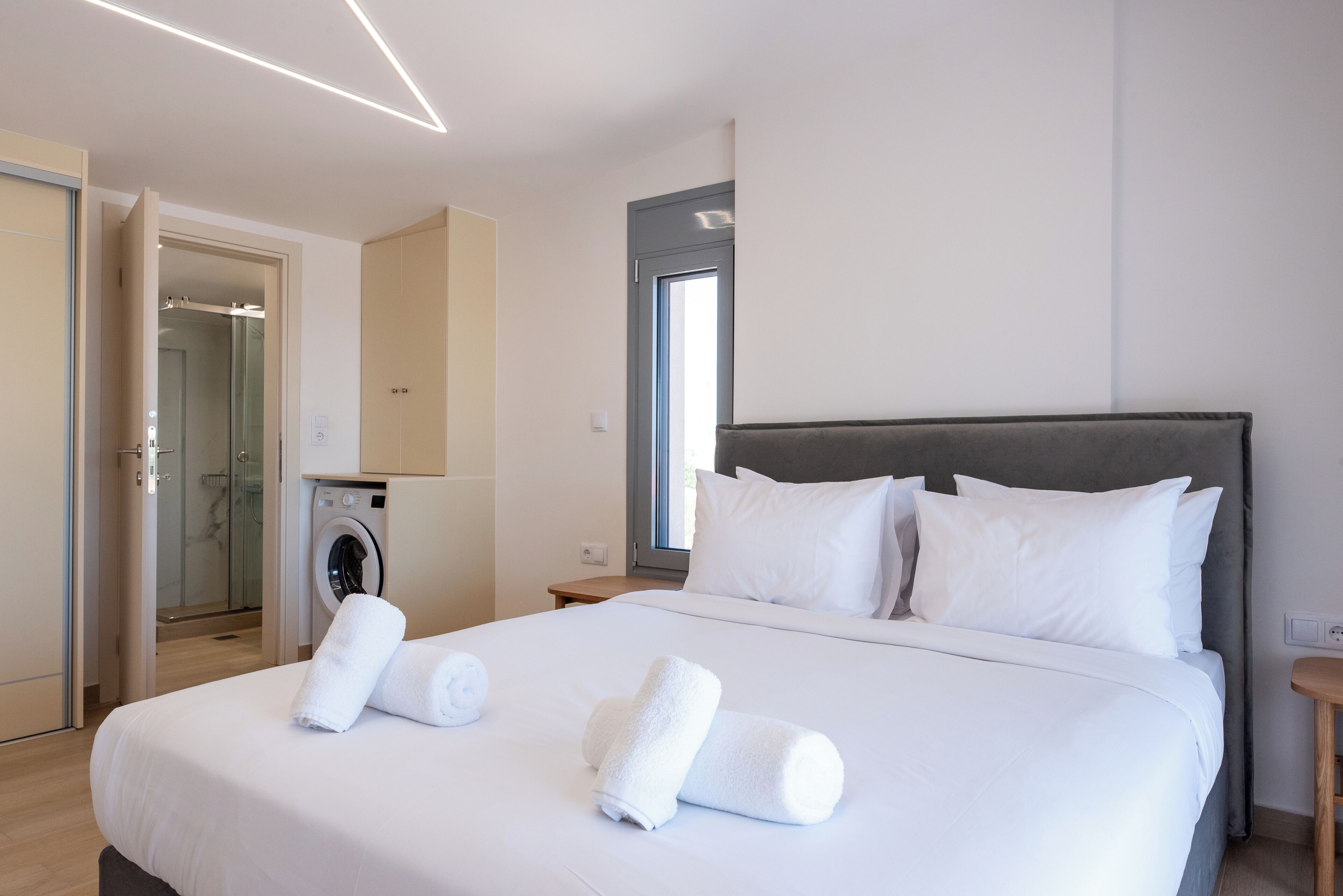 A hotel room with a bed, a washing machine, and a shower area.