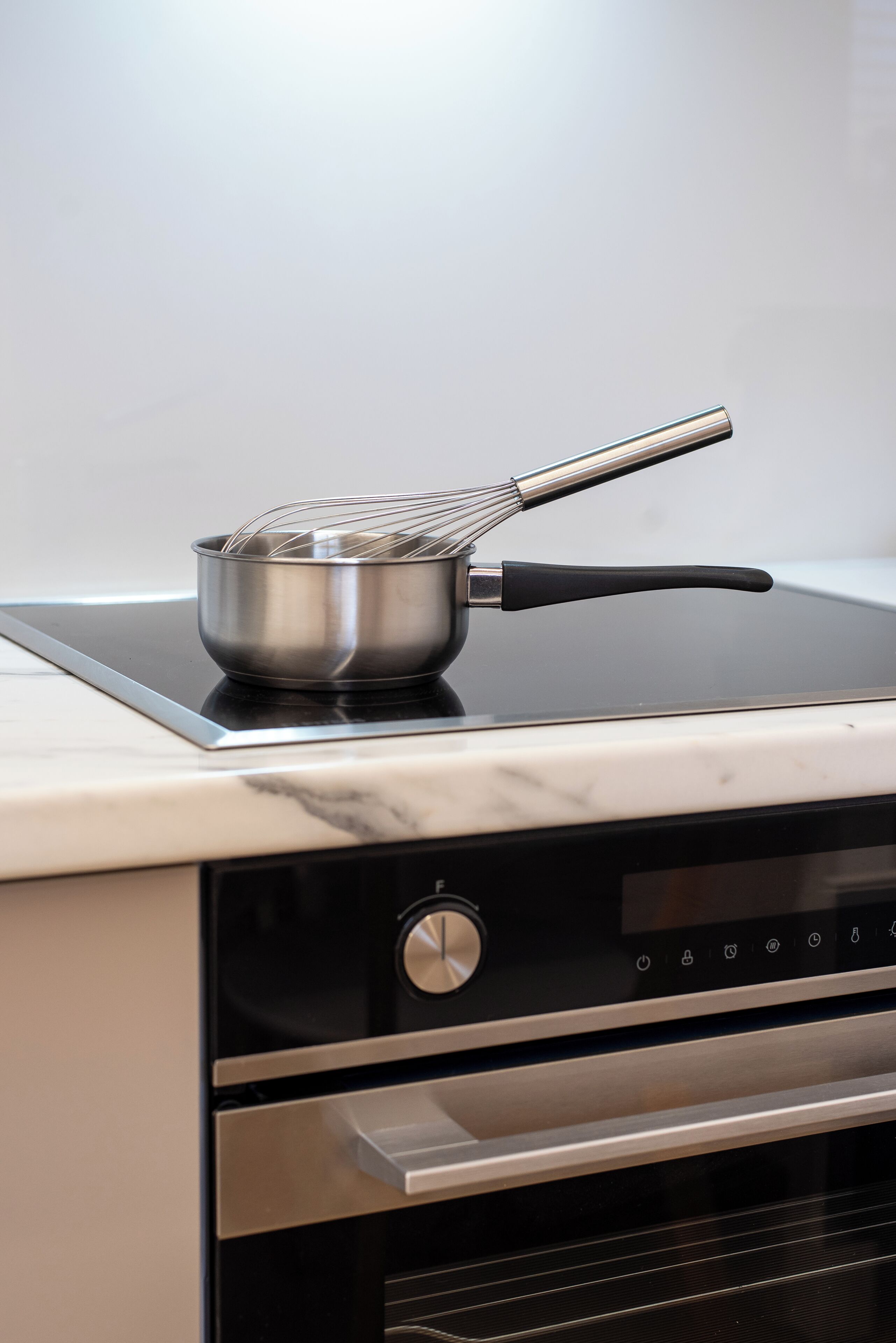 Een keuken met een kookplaat, een pan en een bedieningspaneel.