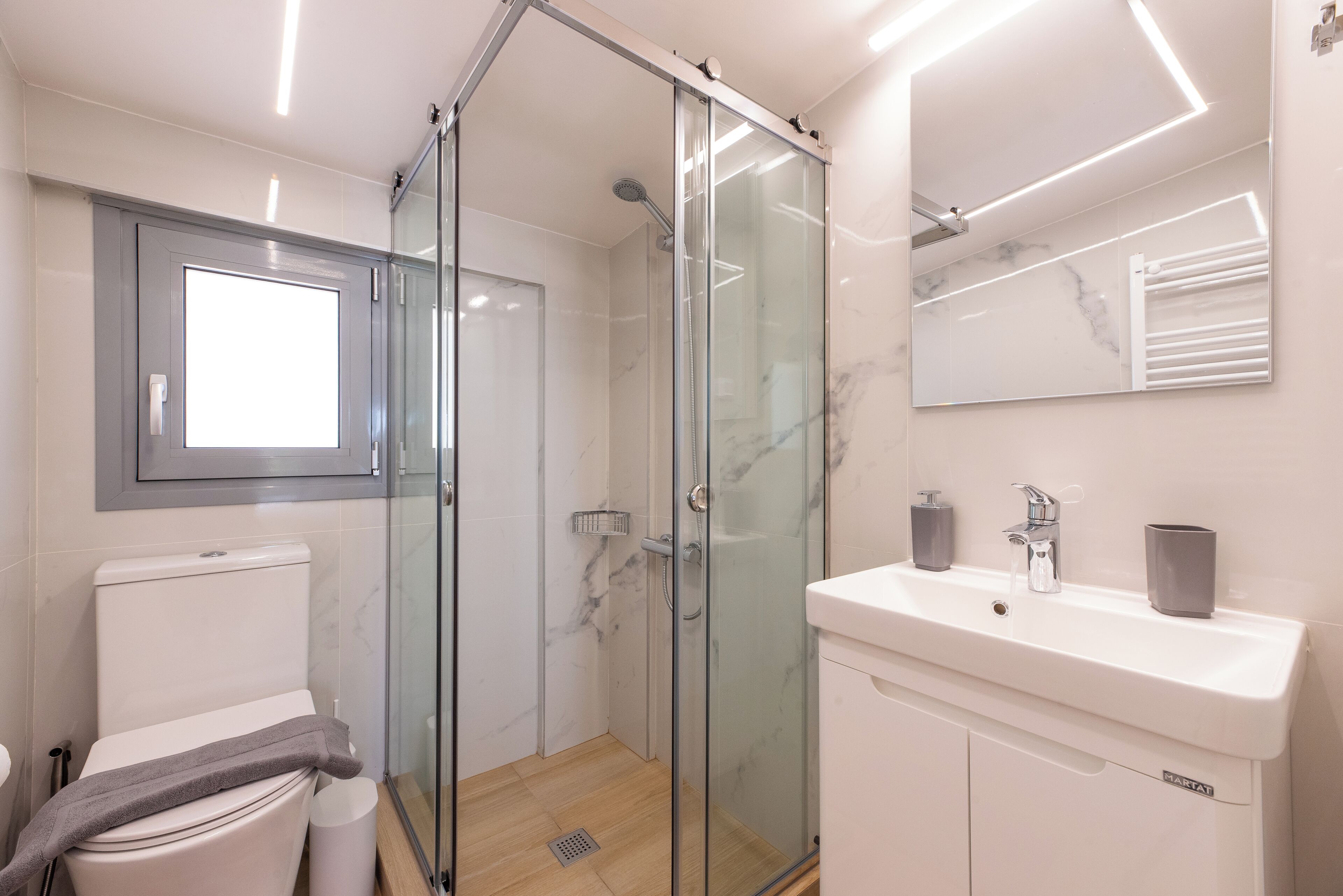 Ein modernes Badezimmer mit Duschkabine, Toilette, Waschbecken und Spiegel.