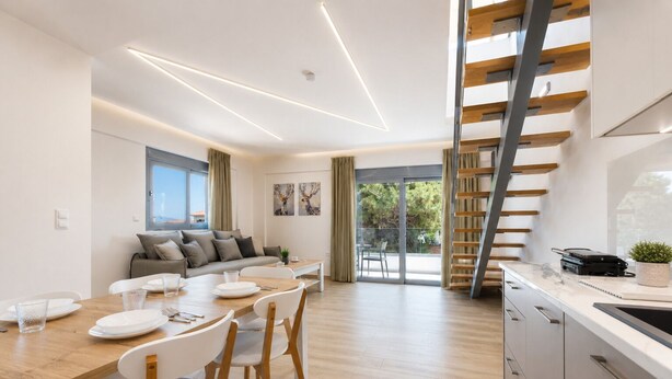 Una cocina moderna con escalera de madera, zona de comedor con mesa y sillas de madera, y un ventanal con vistas a un balcón.