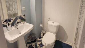 Une salle de bain avec un lavabo blanc, des toilettes et un espace douche.