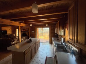 Un interior de madera con una cocina que cuenta con una isla central, una mesa de comedor y sillas.
