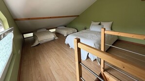 A room with a sloped ceiling, wooden beams, a bunk bed, and a window.
