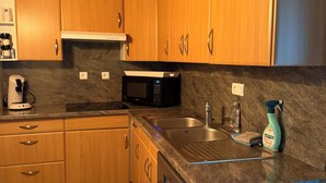 A kitchen with wooden cabinets, a microwave, a sink, and a dishwasher.