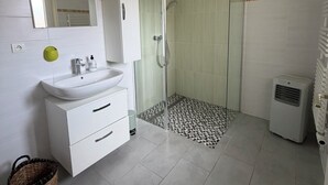 A bathroom with a white sink, mirror, cabinet, shower, and tiled floor.