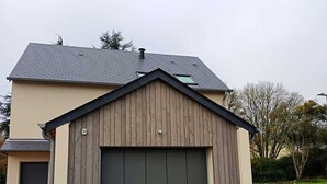 Un bâtiment d’un seul étage, doté d’une porte de garage, d’un petit abri attenant et d’un toit en pente.