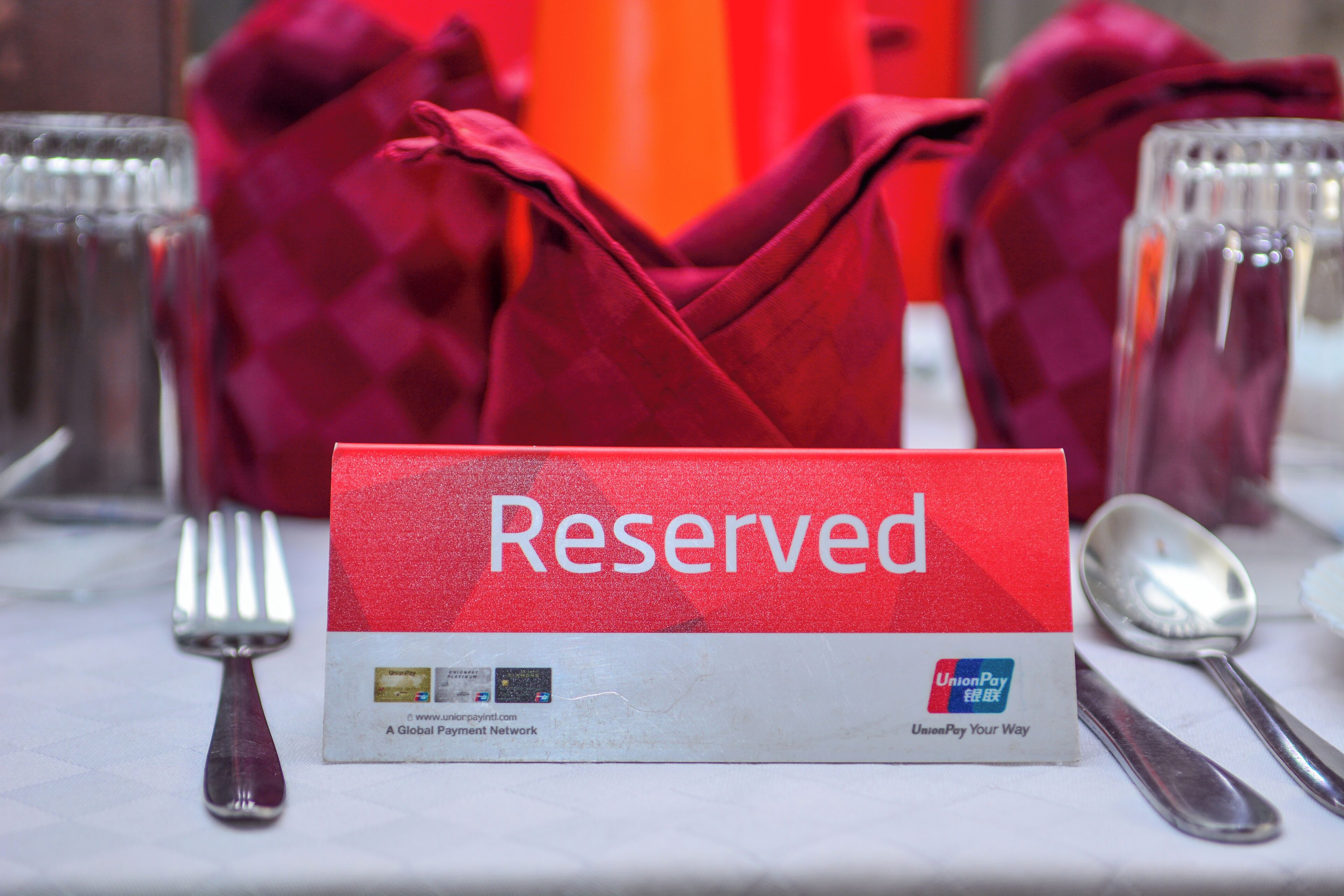 Ein gedeckter Tisch mit einem 'Reserved'-Schild, einer Gabel, einem Löffel und einem Glas.
