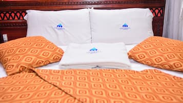 Una habitación de hotel con una cama, almohadas y una manta.