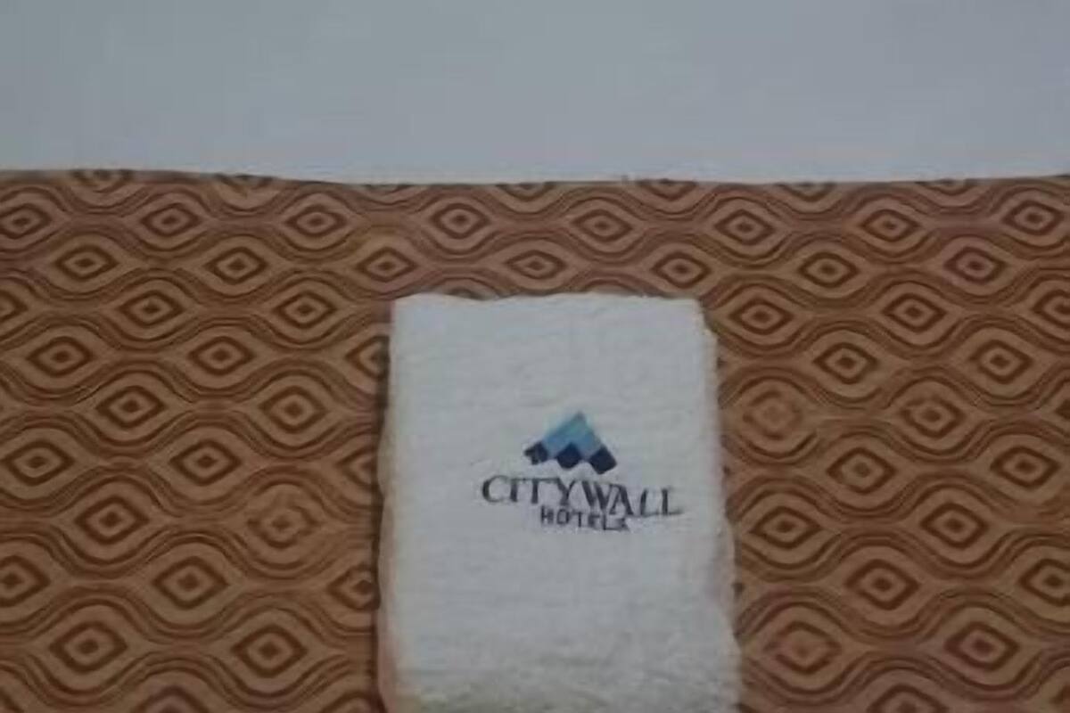 Una cama de hotel con una almohada estampada, una toalla blanca con el logotipo del hotel y una colcha estampada.