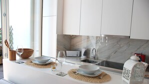 Une cuisine moderne avec des meubles blancs, un pare-feu en marbre et un four encastré.