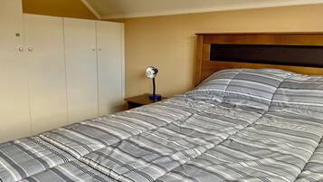 A bedroom with a bed, a nightstand, a desk, and a wardrobe.