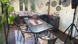A dining area with a glass table, black chairs, a patterned rug, and a hanging plant. - Curico FULL furnished house, central location, roofed parking lot (Curicó)
