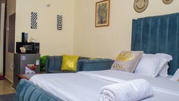 Una habitación de hotel con cama, sofá, microondas y refrigerador.