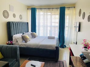 Un dormitorio con cama, sofá, mesa de centro y televisor.