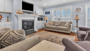 A living room with a fireplace, a sofa, a coffee table, and a TV. - Canal Front Home, Boat Dock, Sleeps 17, Dog Friendly (Surf City)