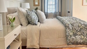 A bedroom with a bed, bedside table, lamp, and a window with curtains.