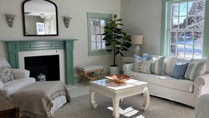 A living room with a fireplace, a sofa, a coffee table, and a large window.