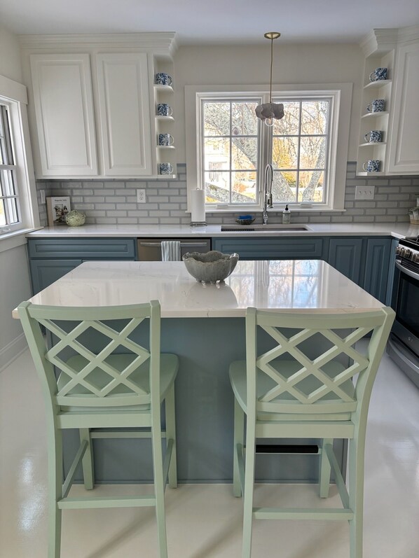 A kitchen with white cabinets, a large island, and blue chairs.