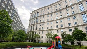 A playground with slides and climbing structures, surrounded by a landscaped area with trees and a building in the background. - Skyline Suites 81 Newport Condotel NAIA T3 (Pasay City)