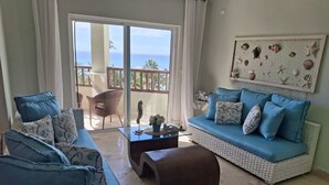 Una sala de estar con un sofá, dos sillones, una mesa de centro y un adorno en la pared.