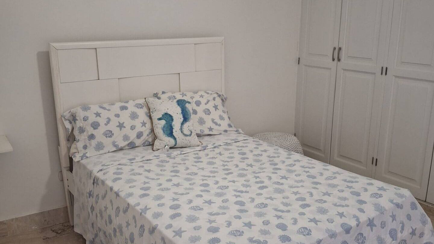 A bedroom with a bed, a nightstand, and a wardrobe.