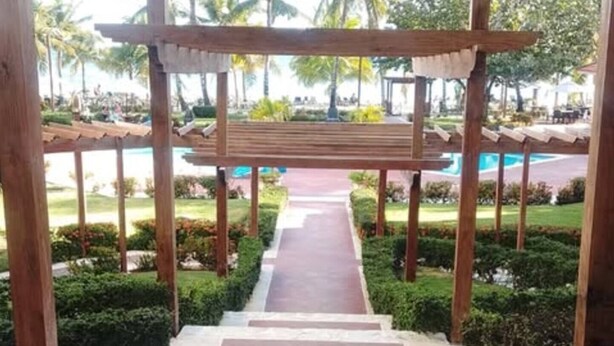 Una estructura de pérgola de madera con un sendero que lleva a una zona de piscina.