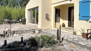 A modern house with a patio area featuring outdoor furniture and a decorative rock arrangement. - La Maison Bleue, your exceptional break in the heart of the Ardèche Gorges (Salavas)