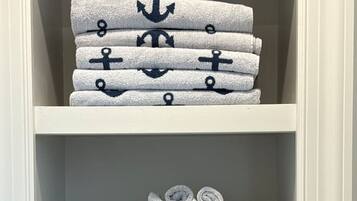 Uno scaffale con asciugamani ordinatamente impilati e decorati con motivi a ancora.