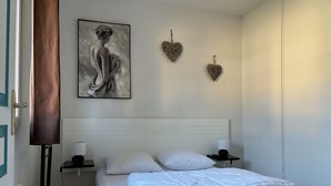 Ett hotellrum med en säng, sängbord, en tavla och dekorativa, hjärtformade väggdekorationer.