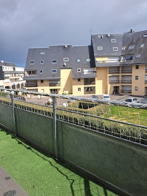 Un immeuble résidentiel à plusieurs étages, doté de balcons, d’un espace de stationnement et d’une pelouse verdoyante.